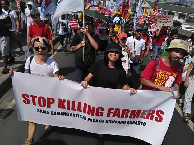 Peasant advocates who work in the art, culture, and knowledge industries march together as SAKA (Sama-samang Artista para sa Kilusang Agraryo or Artists’ Alliance for Genuine Agrarian Reform) on Labor Day, carrying a banner that calls on the state to stop killing farmers. As of this writing, 202 farmers have been killed under the US-Duterte regime in relation to land disputes since he came to power in 2016. The author is one of the marchers carrying the banner. (Photo courtesy of Yo Salazar and SAKA.)