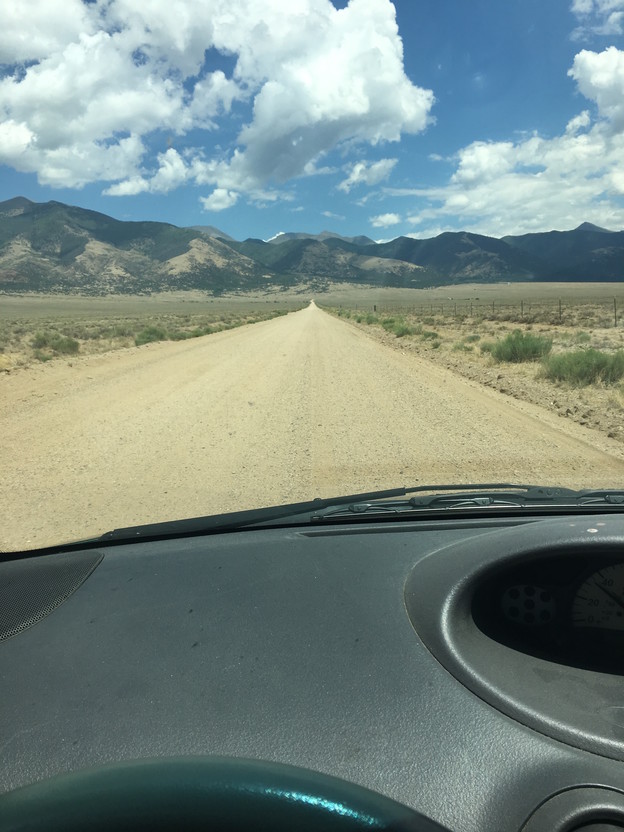 image of a long road that fades into the distance taken from inside a car