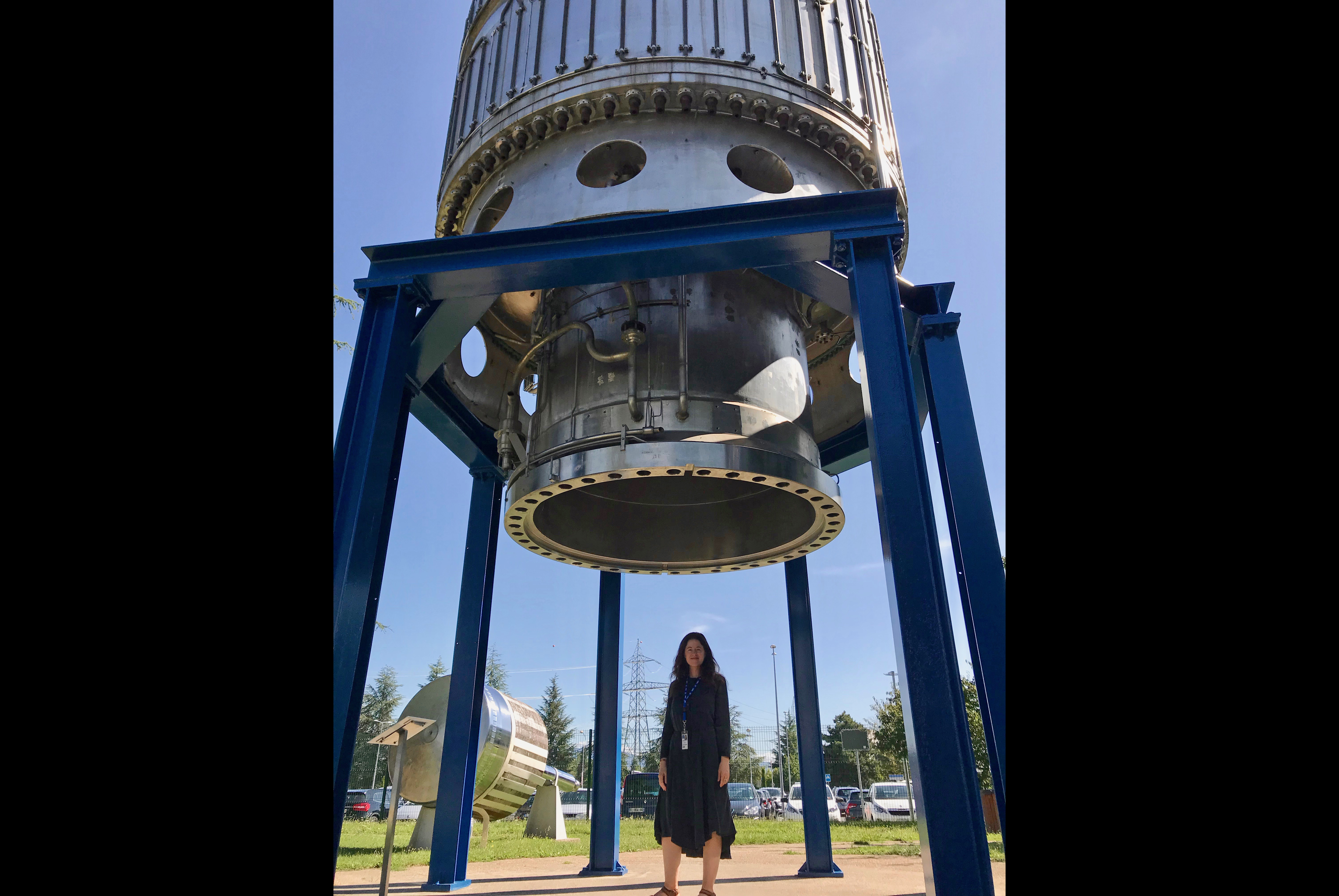 Amy Catanzano at CERN under the Big European Bubble Chamber in the garden of decommissioned experiments, 2019. For this second visit, she was sponsored as a research artist and funded by the Outreach office of the ATLAS Experiment at the Large Hadron Collider. Catanzano has been awarded funding by Wake Forest University and CERN for a third visit to pursue collaborative projects. Amy Catanzano at CERN under the Big European Bubble Chamber