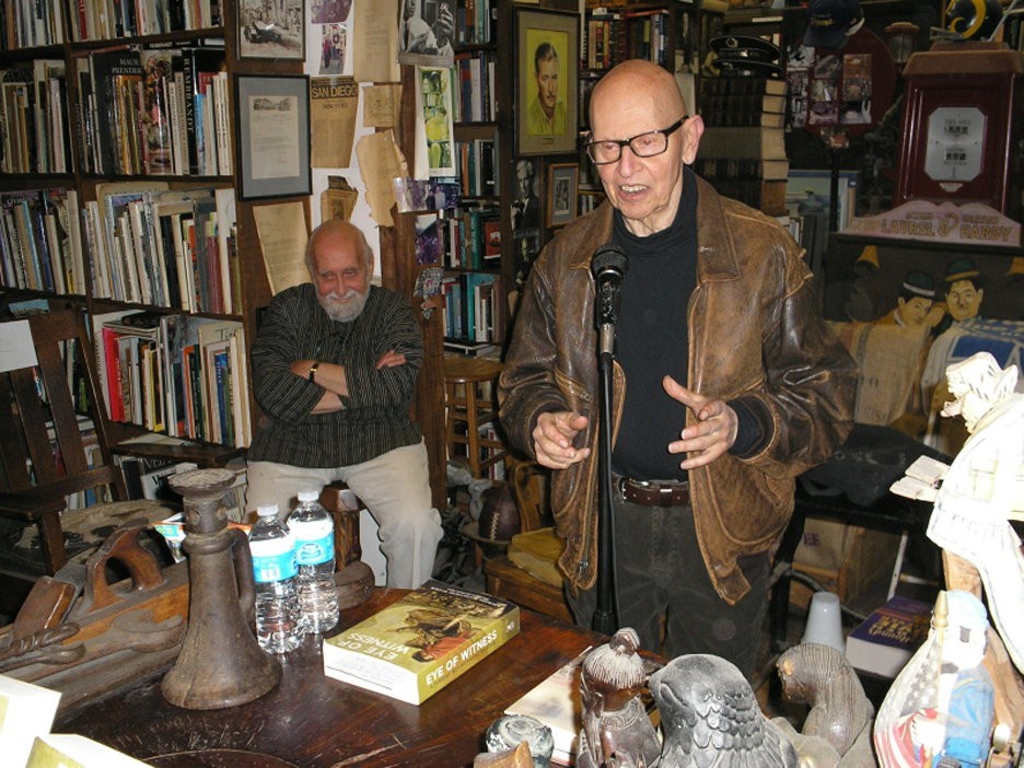 David Antin talking while Jerome Rothenberg listens in the background (photo by D.G. Wills) David Antin talking while Jerome Rothenberg listens in the background (photo by